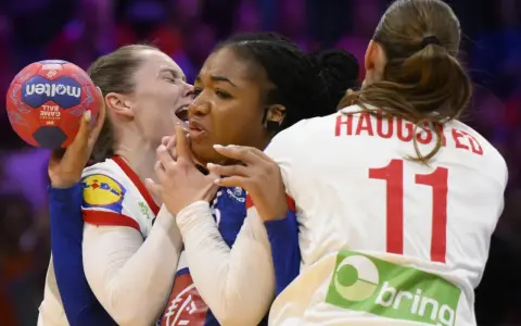 Zacięta walka na boisku! Piłka ręczna między Francją a Danią. Zawodniczka z piłką walczy o pozycję, podczas gdy rywalki próbują ją zatrzymać.