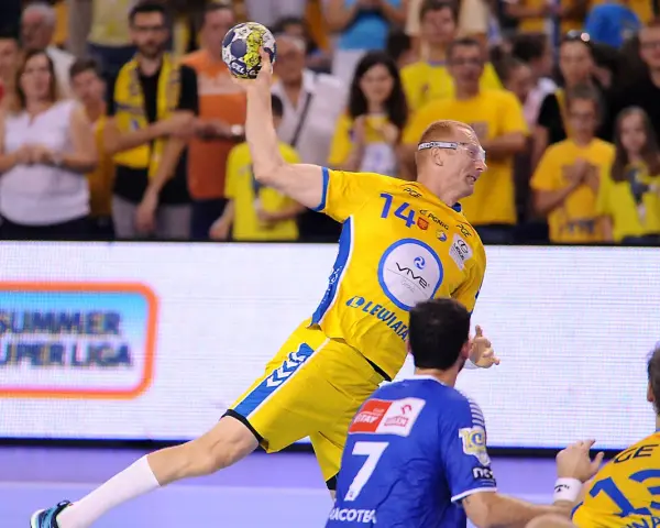 Piłkarz ręczny w żółtej koszulce z numerem 14 rzuca piłkę podczas eliminacji mistrzostw europy w piłce ręcznej grupa polska.