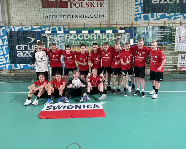 Drużyna piłki ręcznej z numerami na koszulkach, w tym Damian Borkowski, świętuje zwycięstwo.