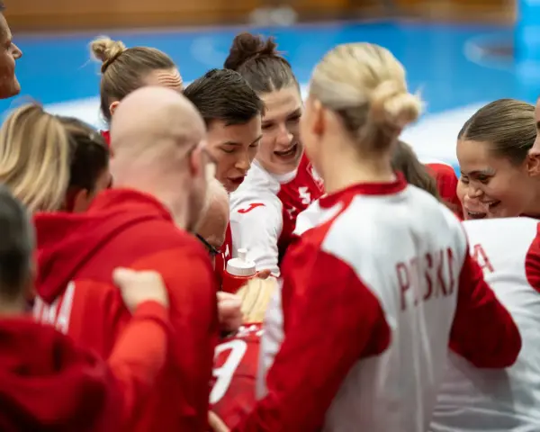 Drużyna piłki ręcznej w czerwonych strojach, zjednoczona przed meczem. Emocje i determinacja na twarzach zawodniczek podczas mistrzostw świata.