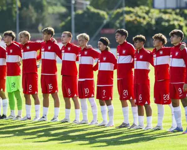 Drużyna Polski na Mistrzostwach Europy do lat 17. Piłkarze w czerwonych strojach z białymi pasami stoją w rzędzie, gotowi do meczu.
