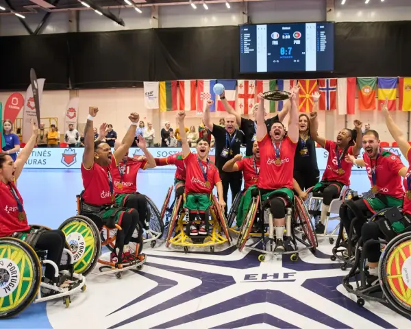 Drużyna Portugalii w piłce ręcznej na wózkach świętuje zwycięstwo. Na ekranie wynik meczu, a w tle flagi państwowe i logo EHF.