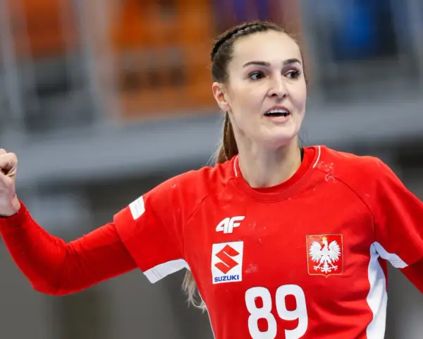 Kinga Achruk, zawodniczka z numerem 89 na czerwonej koszulce, unosi zaciśniętą pięść w geście triumfu.