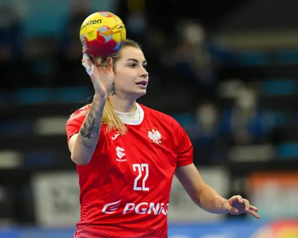 Aleksandra Rosiak w akcji, rzuca piłkę ręczną. Zawodniczka w czerwonej koszulce z numerem 22.