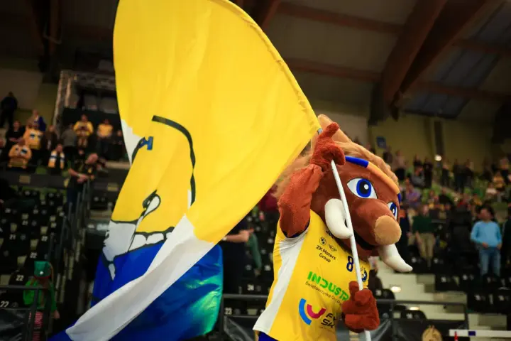 Maskotka z wielką żółtą flagą na meczu w Kielcach.