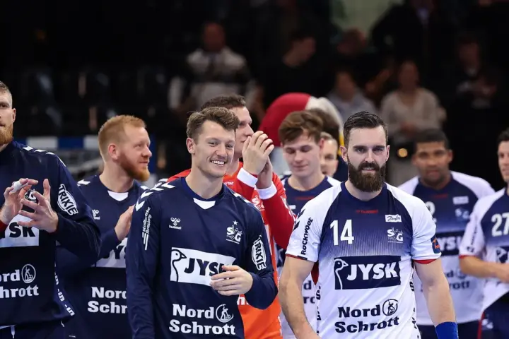 Emil Jakobsen z brodą i numerem 14 na koszulce, w otoczeniu drużyny piłkarzy ręcznych.