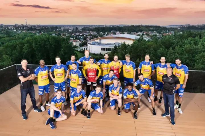Drużyna piłkarzy ręcznych Vive Kielce pozuje do zdjęcia na tle panoramy miasta.