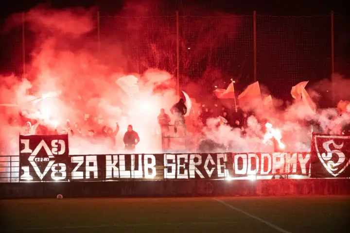 Fani z piłą ręczną, czuwaj przemyśl! Tłum kibiców z racami i flagami tworzy czerwony dym.