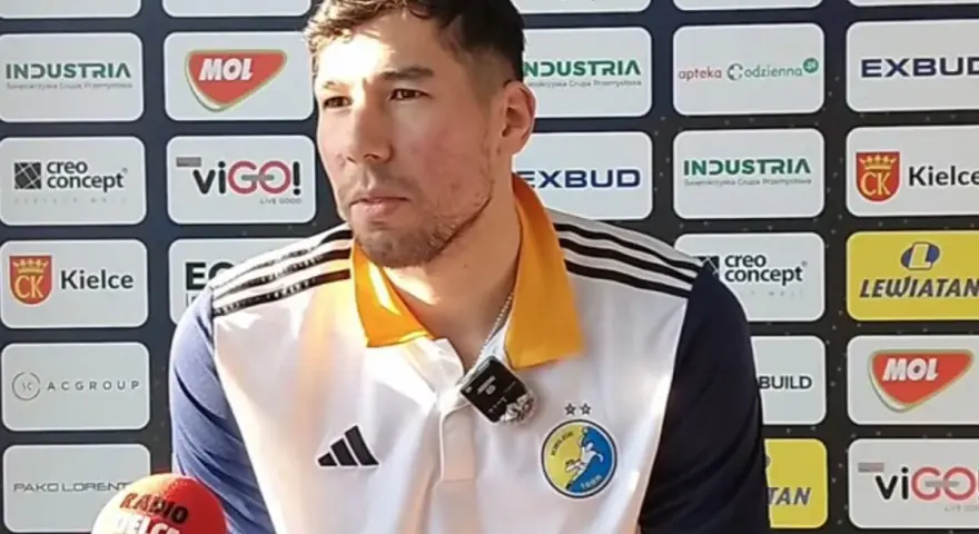 Daniel Dujshebaev w koszulce z herbem klubu, przed ścianką sponsorską z logo "Industria Kielce".