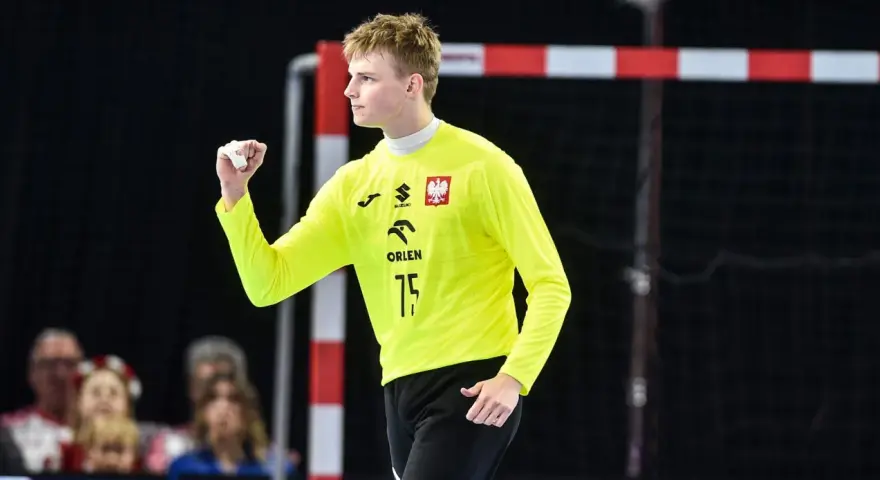Marcel Jastrzębski, młody bramkarz w żółtej koszulce z orłem, zaciśniętą pięścią świętuje udaną interwencję.