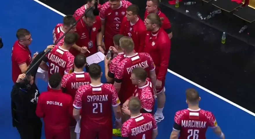 Drużyna piłki ręcznej Polska w czerwonych strojach z białymi detalami, podczas narady taktycznej przed meczem z Niemcami.