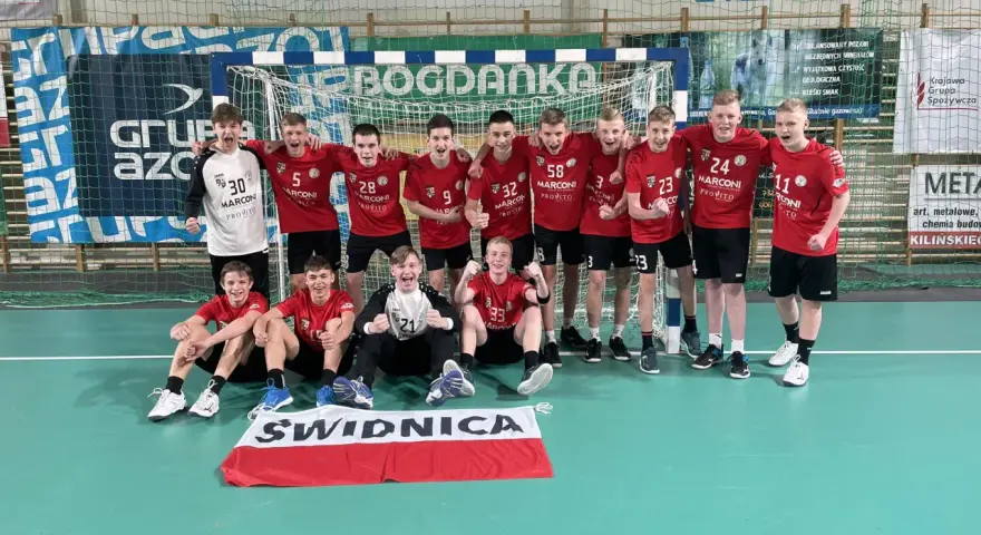 Drużyna piłki ręcznej z numerami na koszulkach, w tym Damian Borkowski, świętuje zwycięstwo.