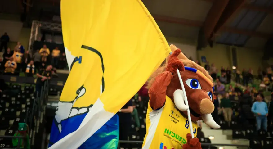 Maskotka z wielką żółtą flagą na meczu w Kielcach.
