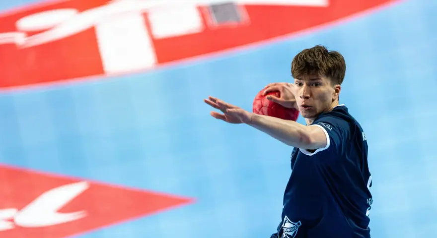 Kamil Skiba w akcji, z piłką w dłoni, gotowy do rzutu.