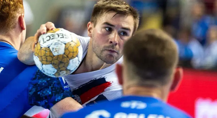 Piłkarz ręczny Luc Steins z piłką w ręku, otoczony przez obrońców.