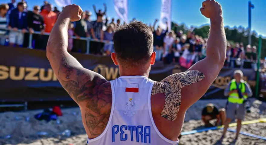 Hubert Wolski, z podniesionymi rękami, świętuje zwycięstwo. Na koszulce widnieje godło Polski i napis "PETRA".