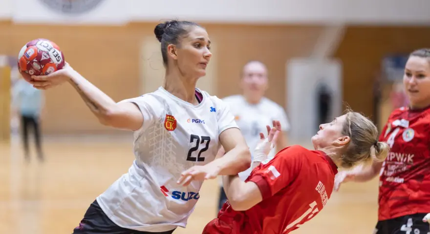 Piłkarka Suzuki Korona Handball Kielce rzuca piłkę. Rywalka w czerwonej koszulce próbuje ją zablokować.