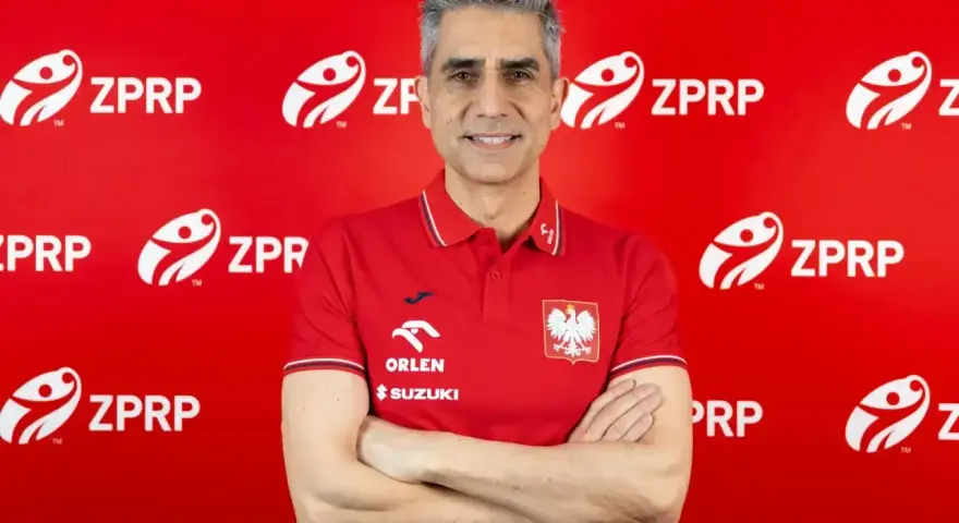 Uśmiechnięty mężczyzna, były trener piłkarzy ręcznych, w czerwonej koszulce z godłem Polski i logo ZPRP.
