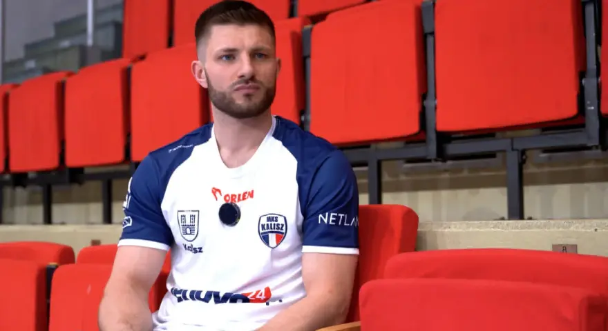Marcel Sroczyk, zawodnik MKS Kalisz, siedzi na czerwonych trybunach.