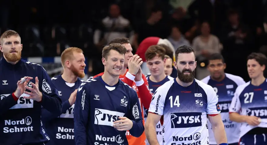 Emil Jakobsen z brodą i numerem 14 na koszulce, w otoczeniu drużyny piłkarzy ręcznych.