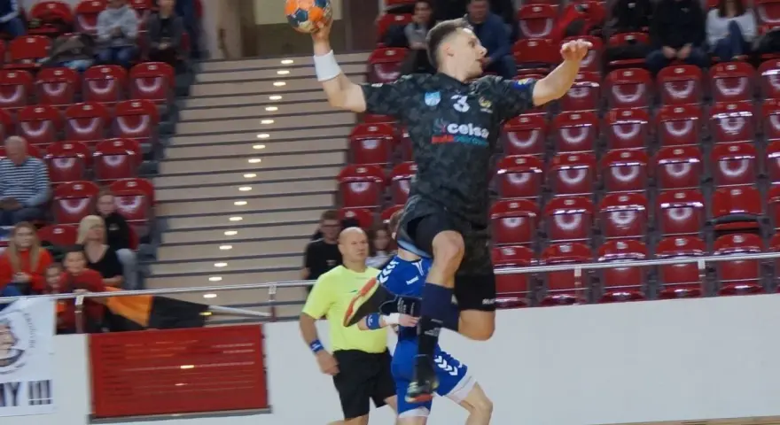 Kacper Grabowski w skoku do rzutu piłką ręczną, próbuje pokonać obronę przeciwnika.