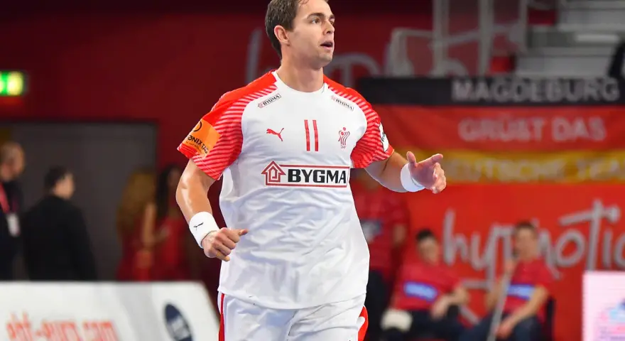 Piłkarz ręczny Rasmus Lauge Schmidt w białej koszulce z czerwonymi rękawami i numerem 11.