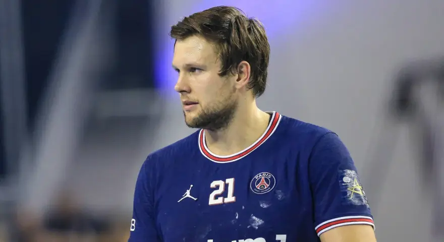 Piłkarz ręczny PSG z numerem 21 na koszulce, skupiony na grze.