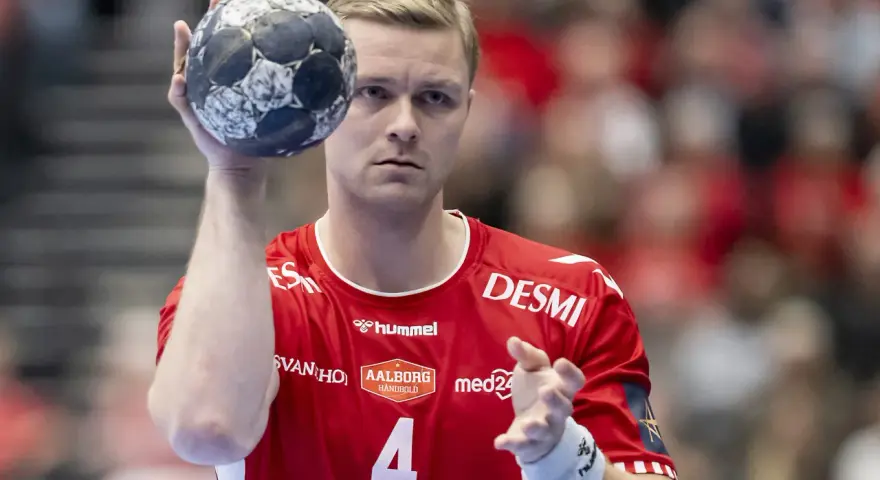 Aron Palmarsson, zawodnik z numerem 4 na czerwonej koszulce, trzyma piłkę do piłki ręcznej, gotowy do rzutu.