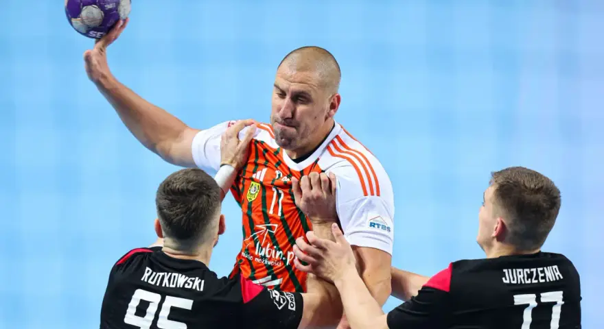 Gracz MKS Piotrkowianin z piłką w ręku, otoczony przez obrońców.
