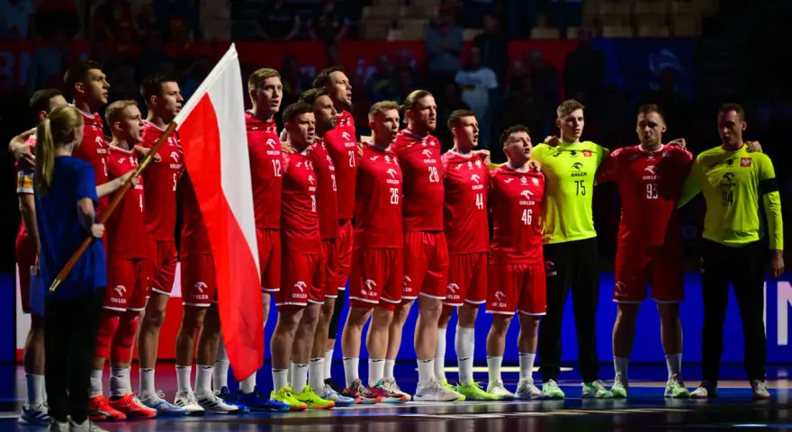 Drużyna piłkarzy ręcznych w czerwonych strojach z polską flagą. To ważny moment w 2 lidze piłki ręcznej.