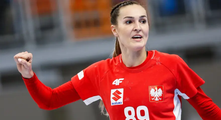 Kinga Achruk, zawodniczka z numerem 89 na czerwonej koszulce, unosi zaciśniętą pięść w geście triumfu.