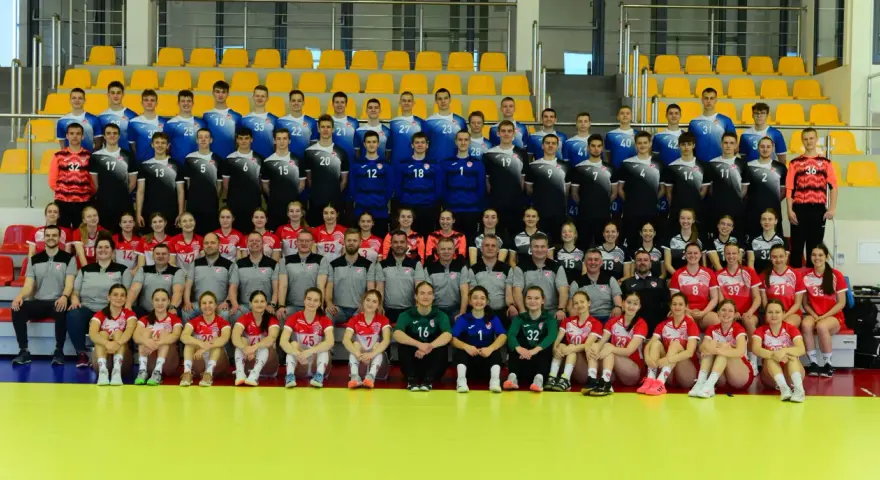 Drużyna siatkarska z numerami na strojach, w tym Marcin Markuszewski, pozuje do zdjęcia grupowego na tle żółtych trybun.