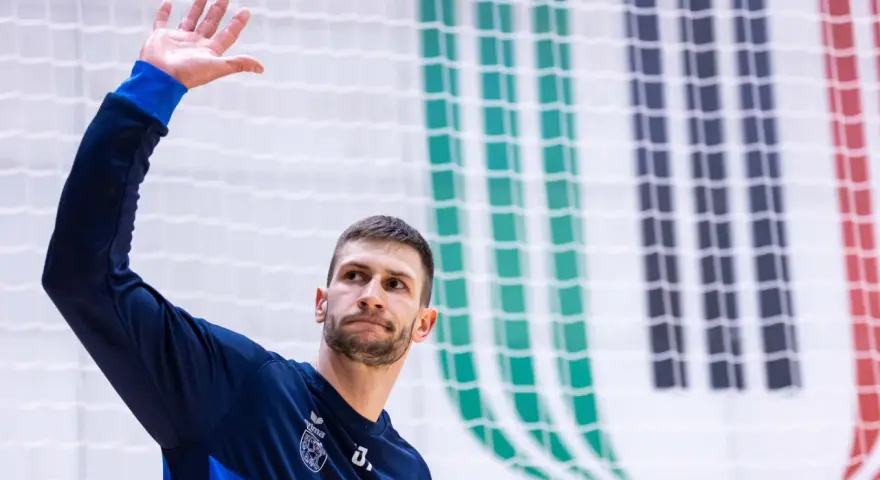 Michał Przybylak wita kibiców, unosząc dłoń.