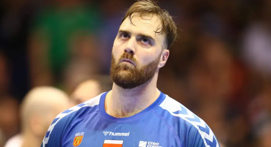 Andreas Wolf, zamyślony zawodnik w niebieskiej koszulce z herbem Kielc, patrzy w górę.