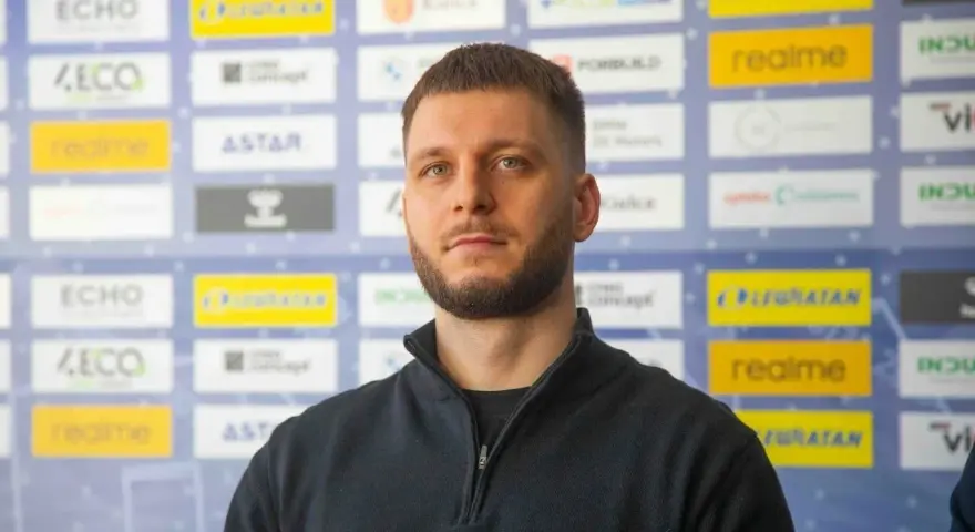 Aleks Vlah, z charakterystyczną brodą i krótką fryzurą, pozuje na tle ścianki z logotypami sponsorów, m.in. "ECHO" i "realme".