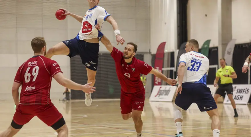 Konrad Małek w skoku po piłkę do ręcznej, broniony przez przeciwnika.