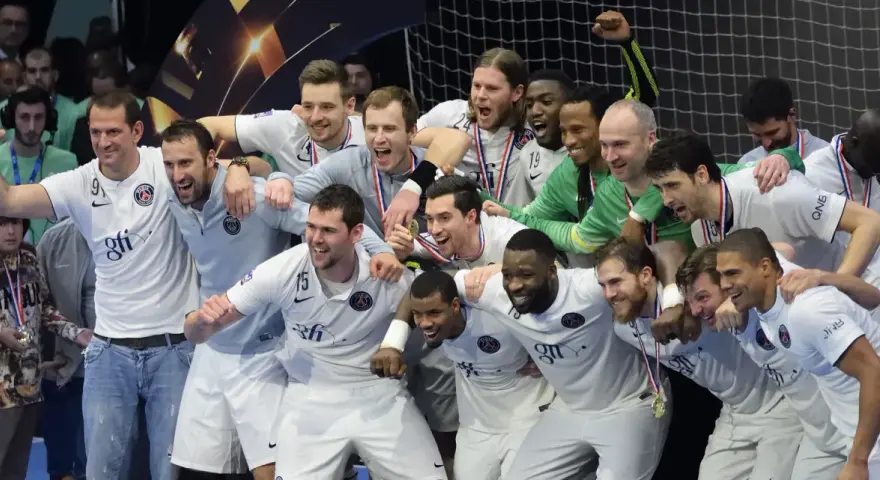Drużyna PSG Handball świętuje zwycięstwo, otoczona kibicami.