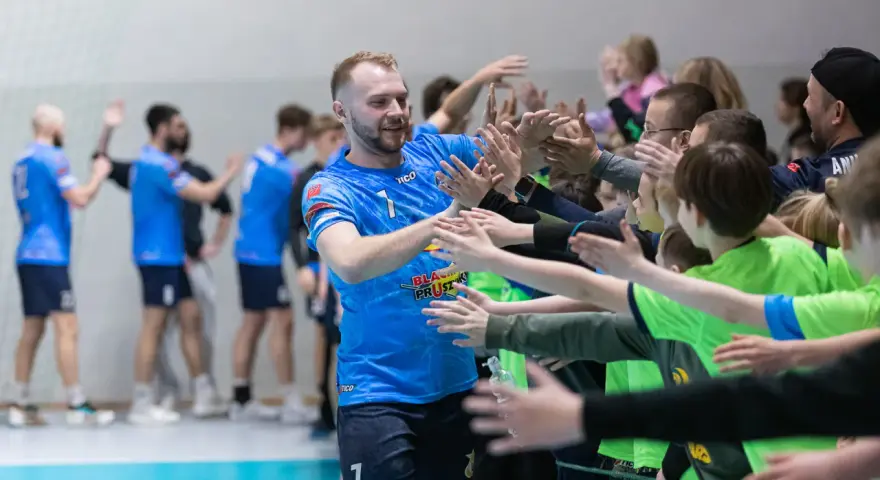 Gracz MKS Wieluń w niebieskiej koszulce z numerem 1 daje "piątki" młodym kibicom.