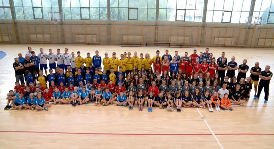 Drużyna Olimp Grodków na hali sportowej. Duża grupa dzieci i młodzieży w strojach sportowych pozuje do wspólnego zdjęcia.