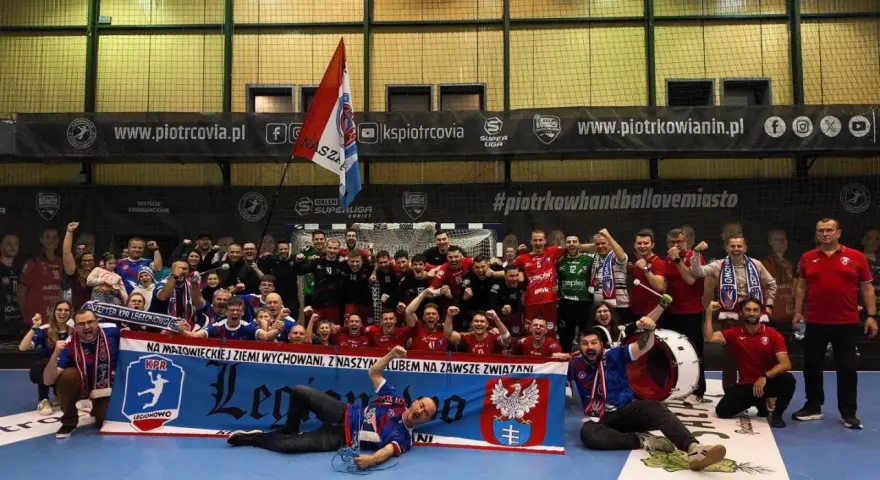 Drużyna KPR Legionowo świętuje zwycięstwo, trzymając transparent z herbem i hasłem.