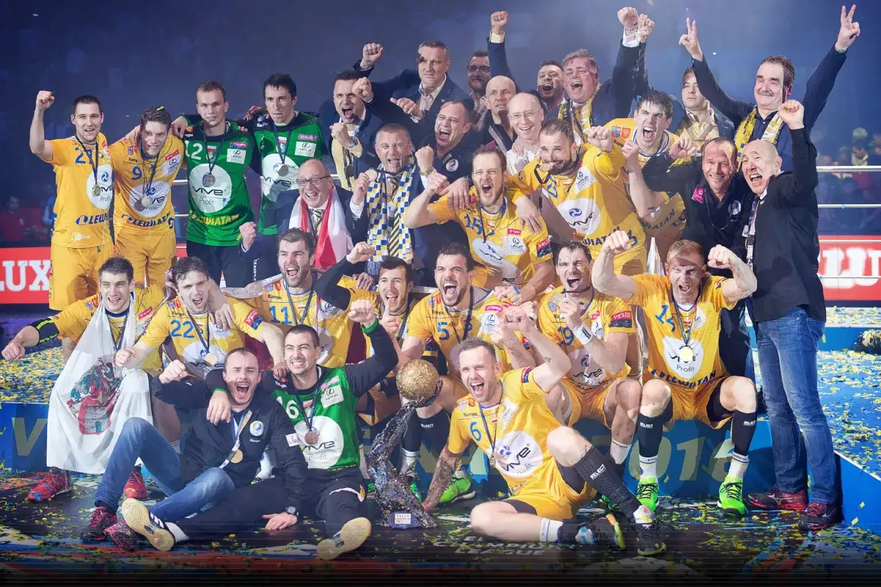 Drużyna Vive Kielce świętuje zwycięstwo, otoczona złotymi medalami i konfetti.