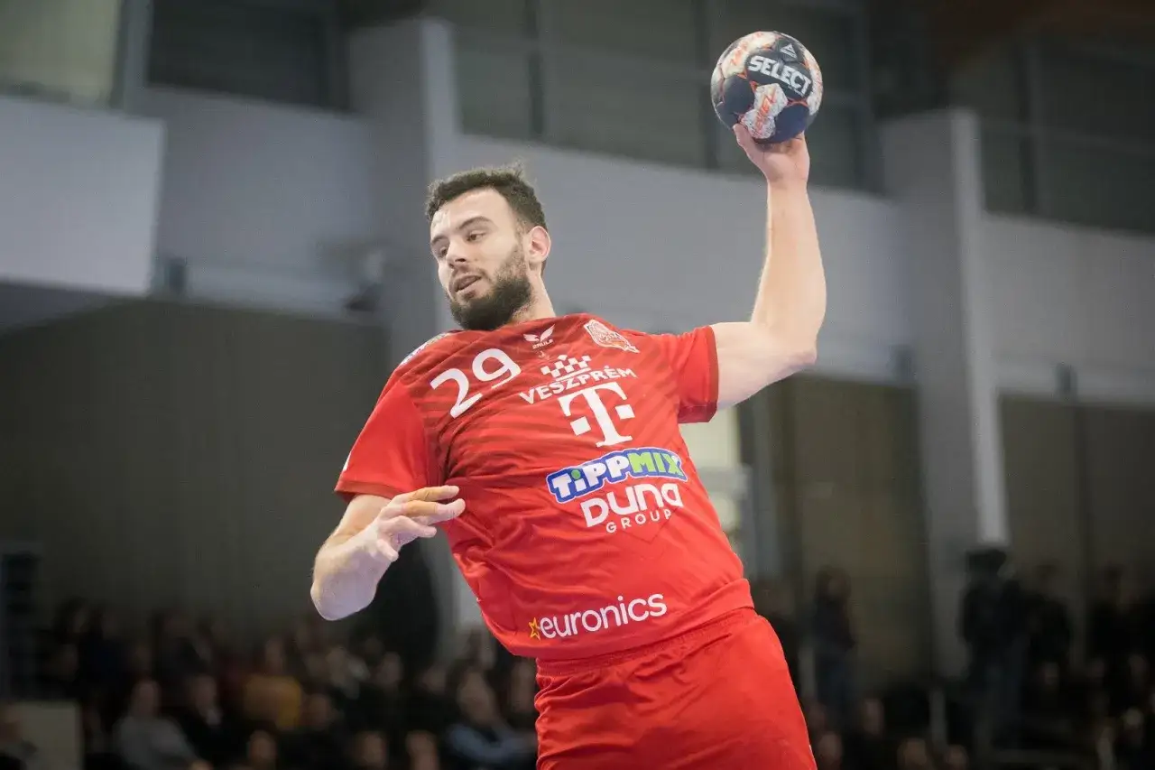 Nedim Remili, zawodnik z numerem 29 na czerwonej koszulce, szykuje się do rzutu piłką do ręcznej.
