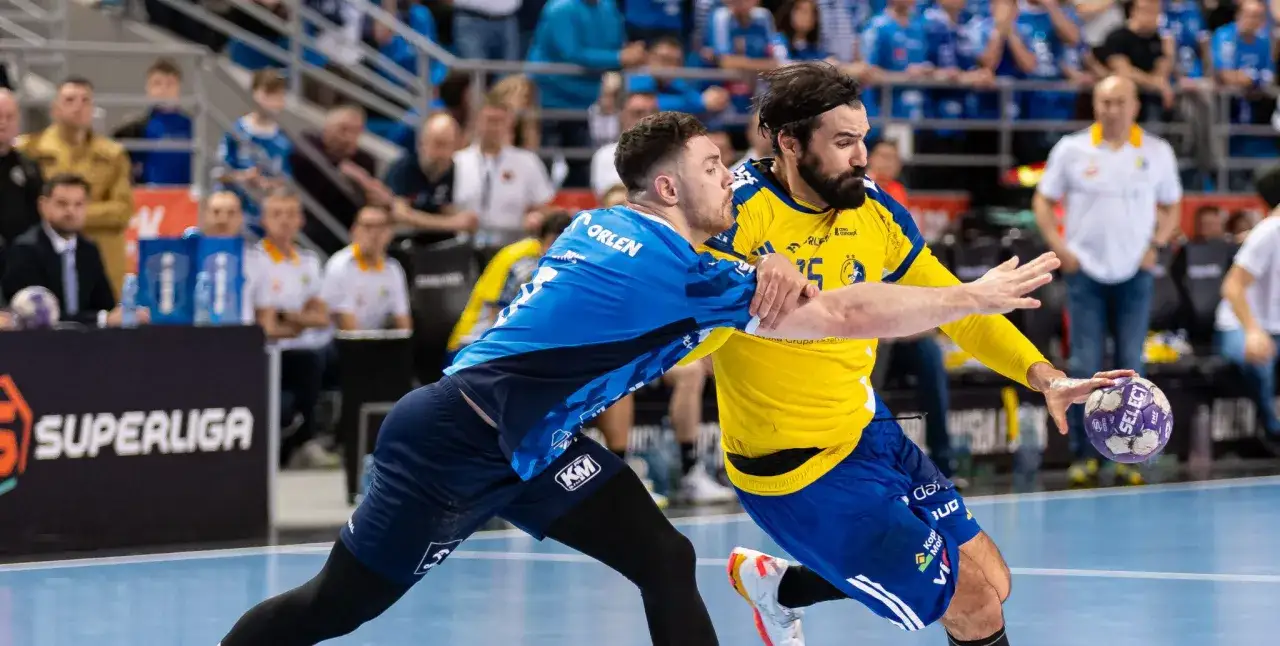 Zacięta walka o piłkę podczas meczu final four w piłce ręcznej. Zawodnik w niebieskiej koszulce próbuje zatrzymać rywala w żółtej.