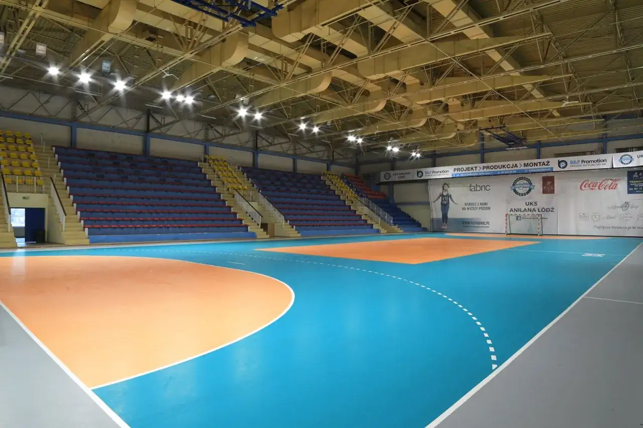 Pusta hala sportowa z trybunami i boiskiem. Na ścianie baner z napisem 