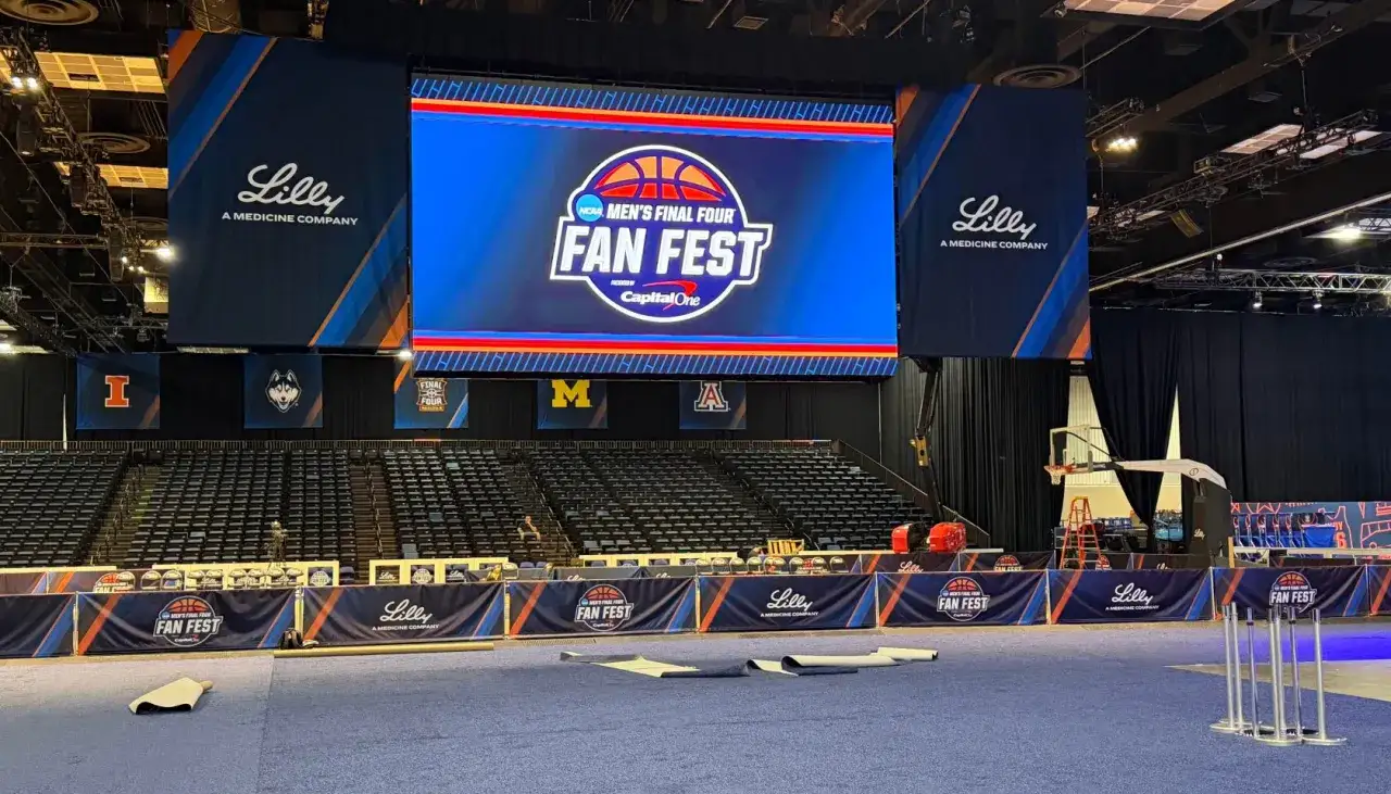 Wielki ekran z logo NCAA Men's Final Four Fan Fest. W tle trybuny i banery uczelni, przygotowania do wydarzenia final four.