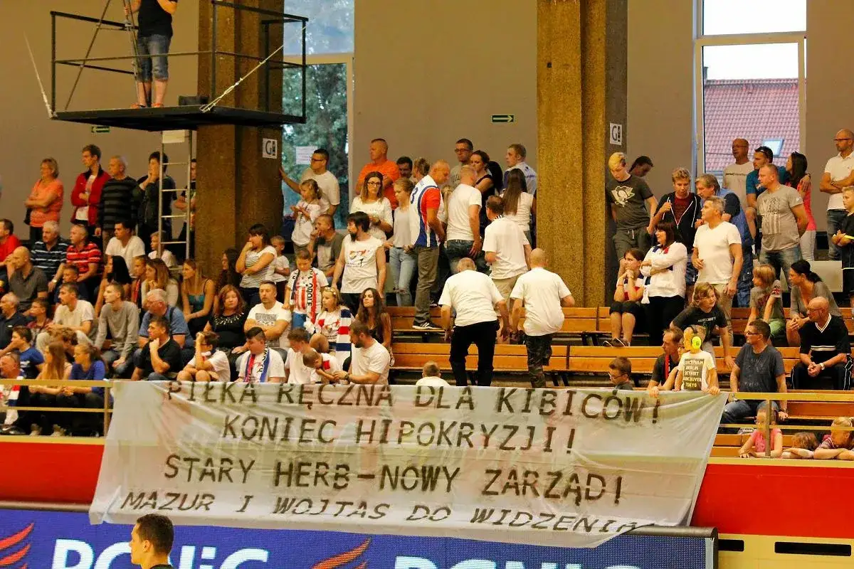 Widownia na meczu piłki ręcznej, kibice z Opola dopingują drużynę. Transparent: 