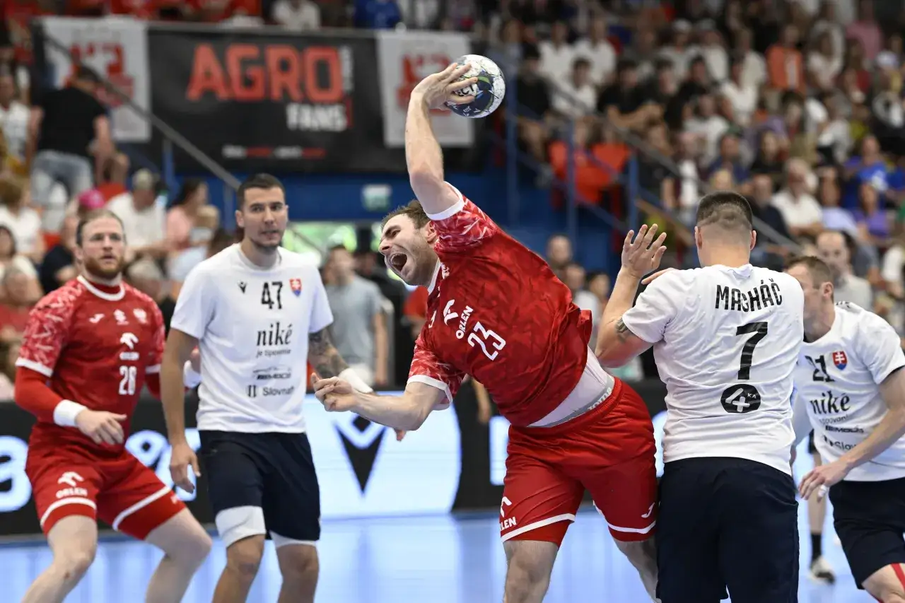 Zacięty mecz piłki ręcznej Polska - Słowacja. Zawodnik w czerwonej koszulce z numerem 23 rzuca piłkę, broniony przez gracza w białej koszulce.