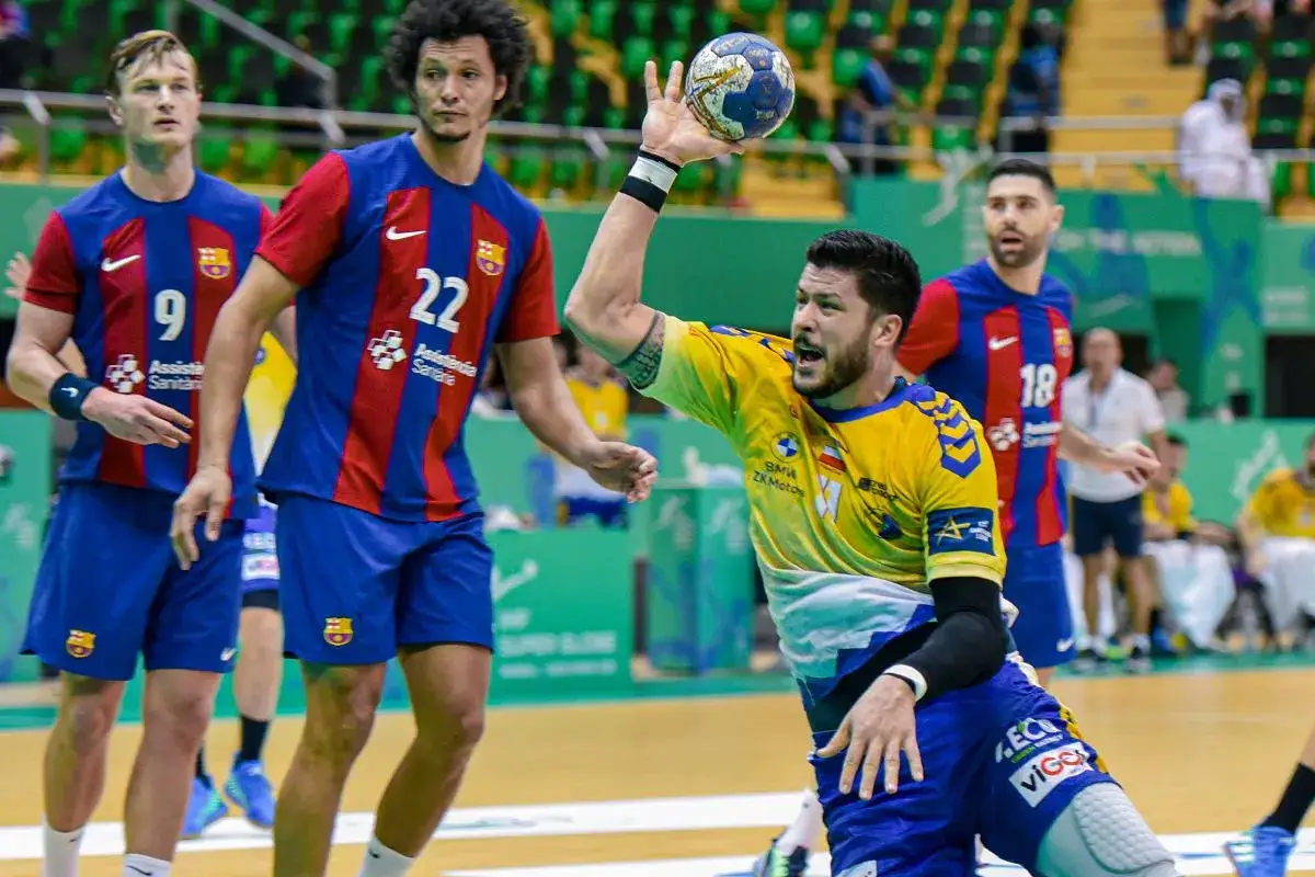 Piłkarz ręczny w ż&oacute;łtej koszulce rzuca piłkę, podczas gdy zawodnicy FC Barcelona w niebiesko-czerwonych strojach obserwują. Vive Barcelona!