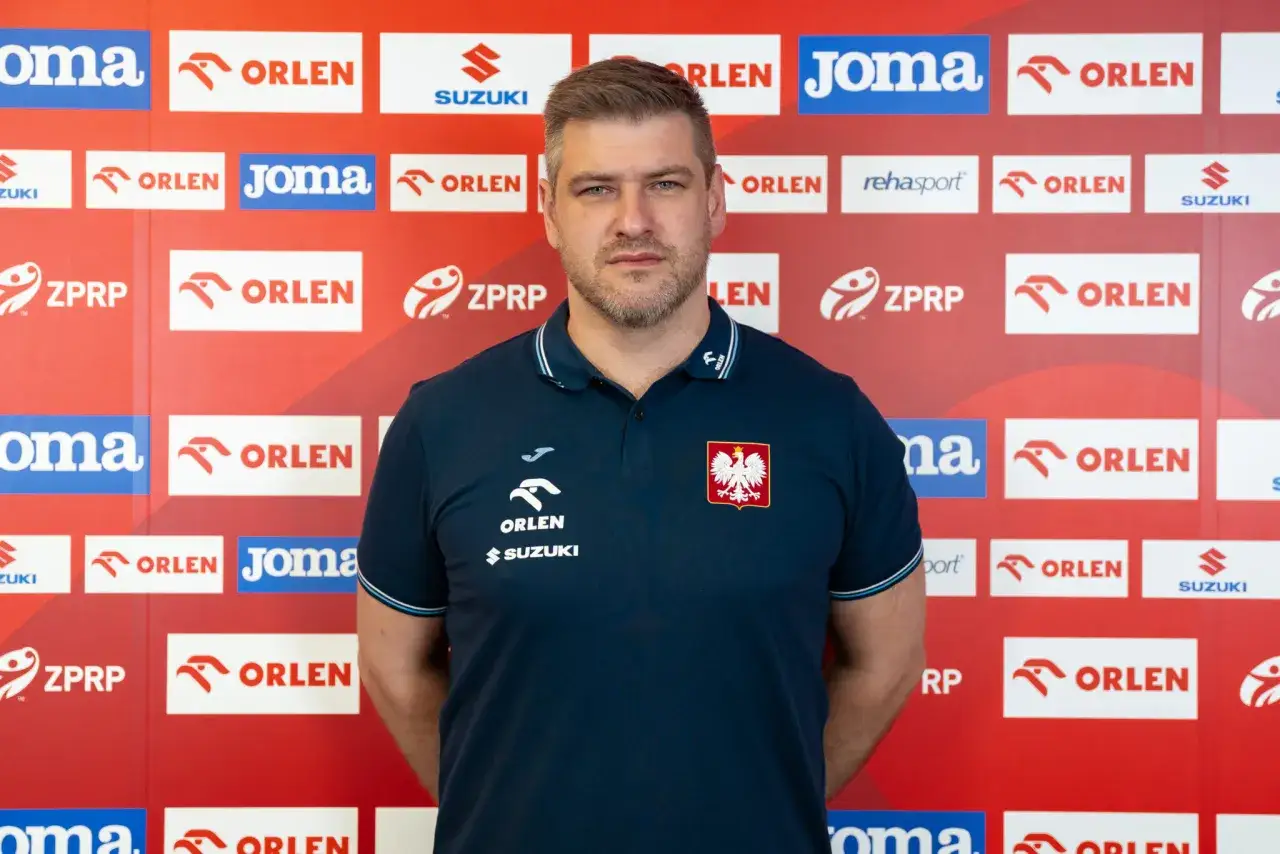 Mężczyzna w granatowej koszulce z orłem na piersi, przypominający Julena Aginagalde, stoi przed ścianką z logo ORLEN.