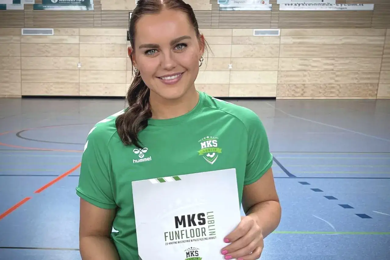 Uśmiechnięta zawodniczka MKS Funfloor Lublin w zielonej koszulce trzyma dyplom.